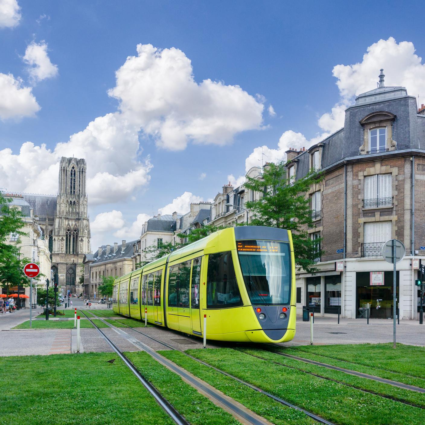 Trams run through the streets and green city landscape of Reims, France