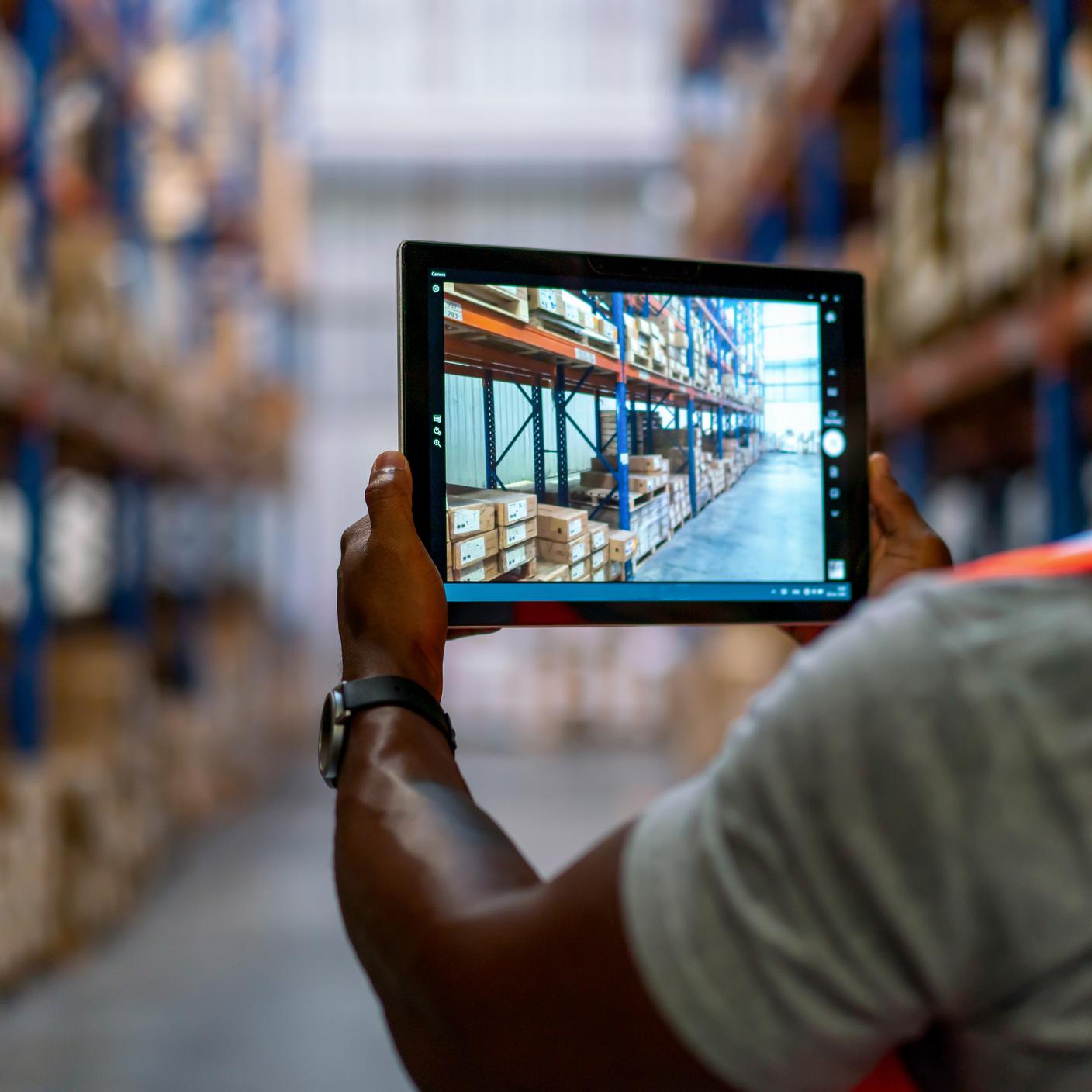 Smart warehouse management system.Worker hands holding tablet on blurred warehouse as background