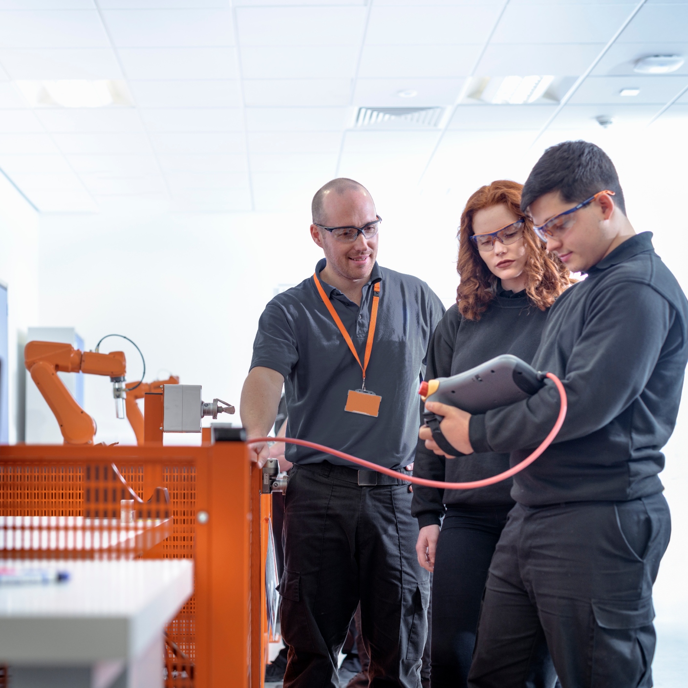 Robotics apprentices using test industrial robots in robotics facility