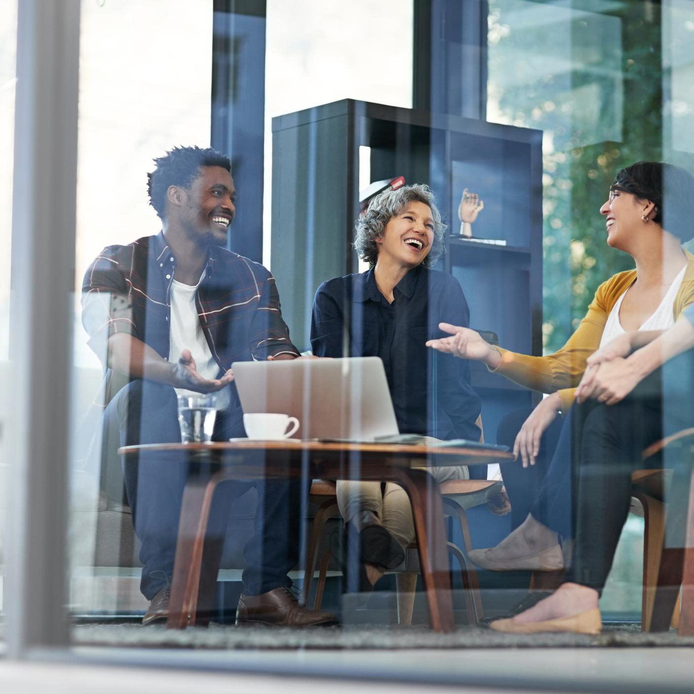Internes Managementmeeting zwischen drei lächelnden Personen.