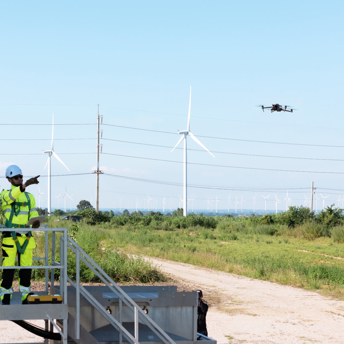 The engineering team is surveying the area to install a large wind turbine for converting wind energy into electricity with a drone