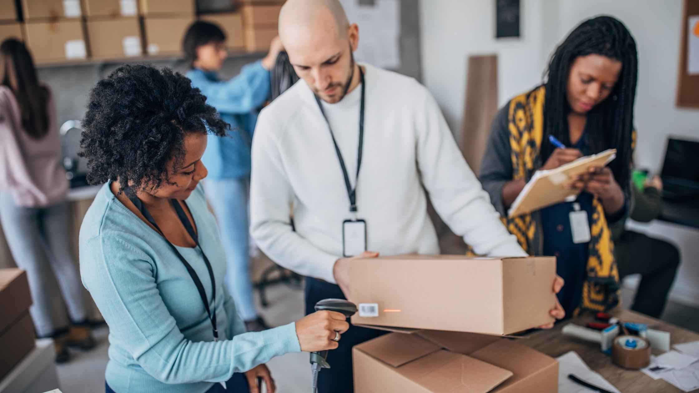 Zugang zum Markt schaffen – Eine multiethnische Gruppe von Männern und Frauen, die im Lager die Kundenbestellungen für den Direktversand zusammenstellen
