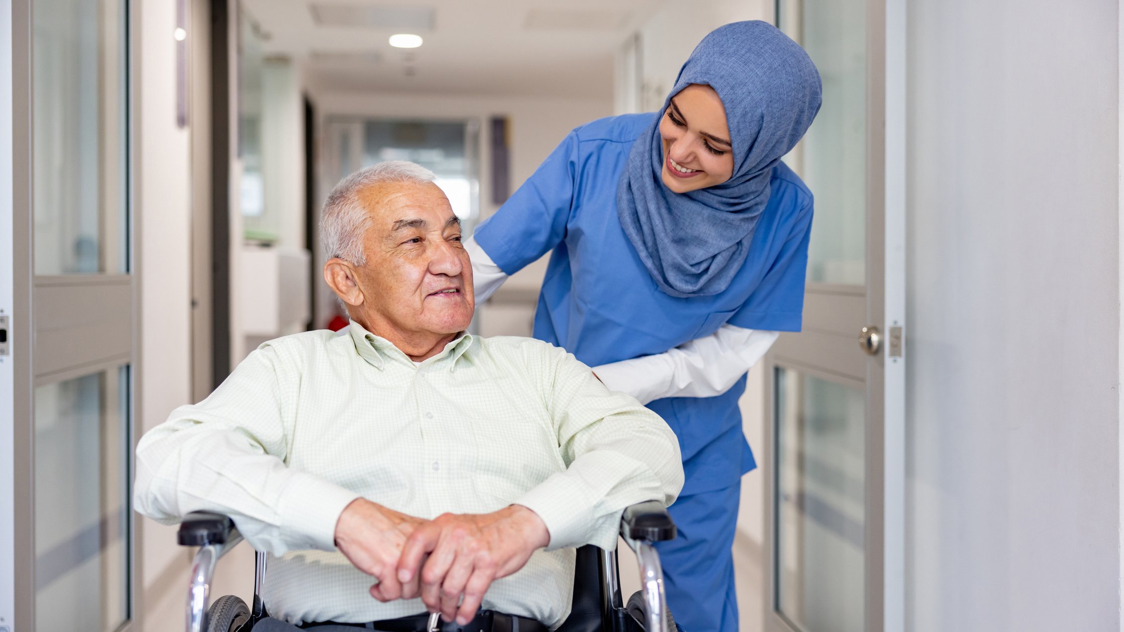 Smiling nurse taking care of a senior patient leaving the hospital in a wheelchair