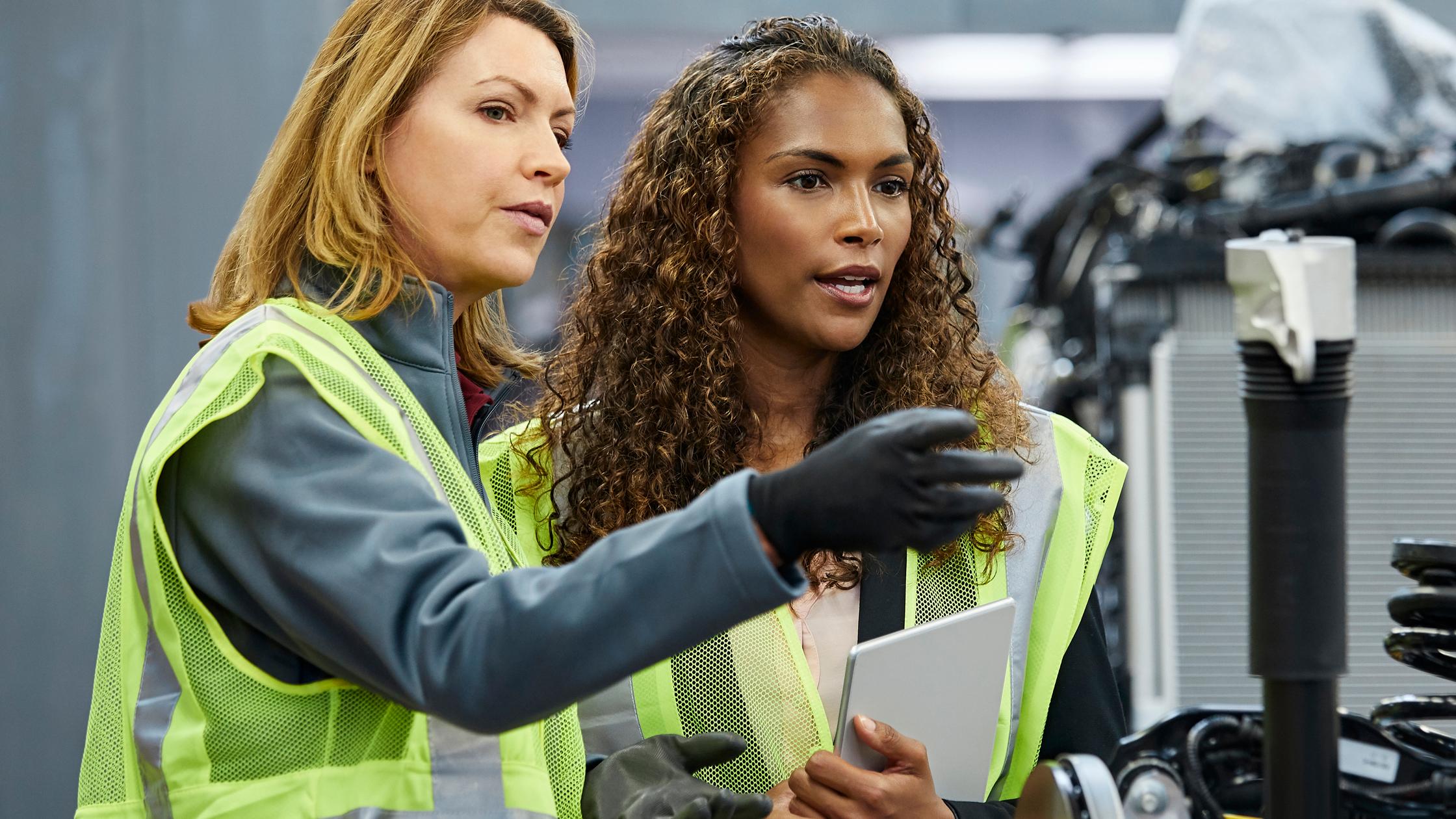 工場で車の部品で同僚を指差す監督