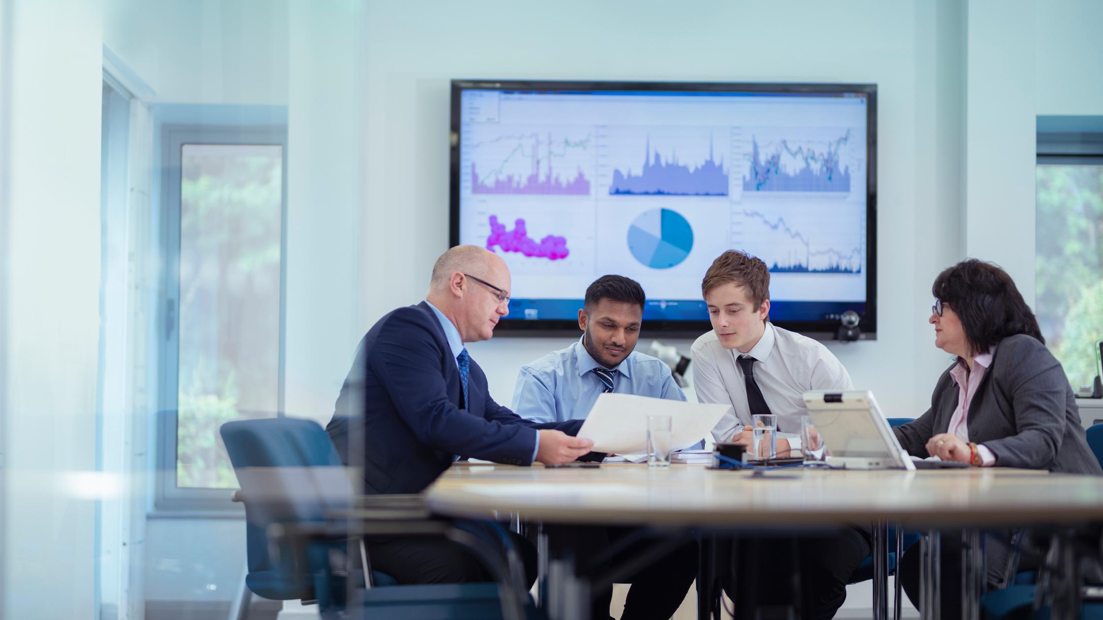 Office workers in meeting with graphs and charts