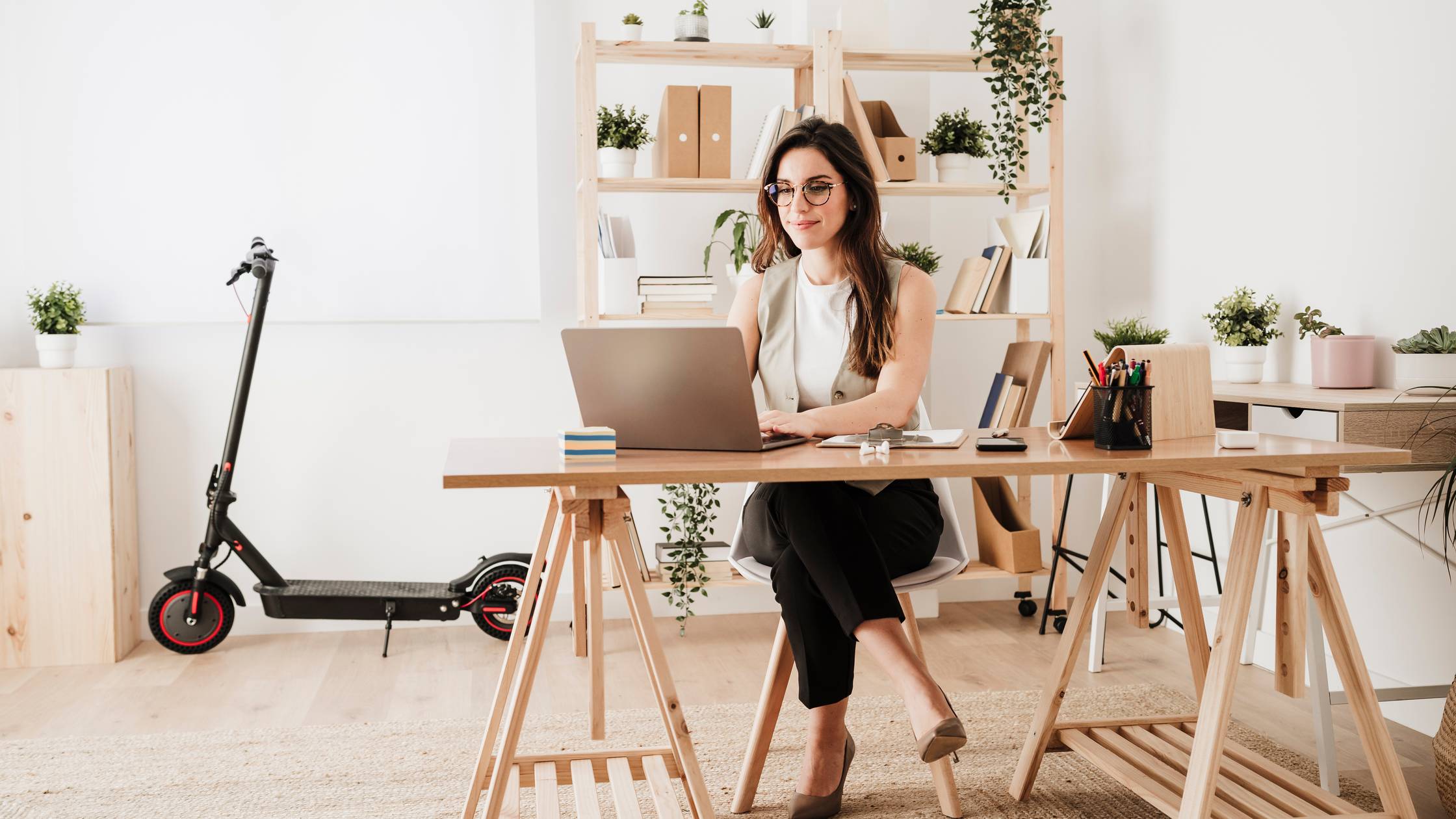 Businesswoman using laptop at desk in office.