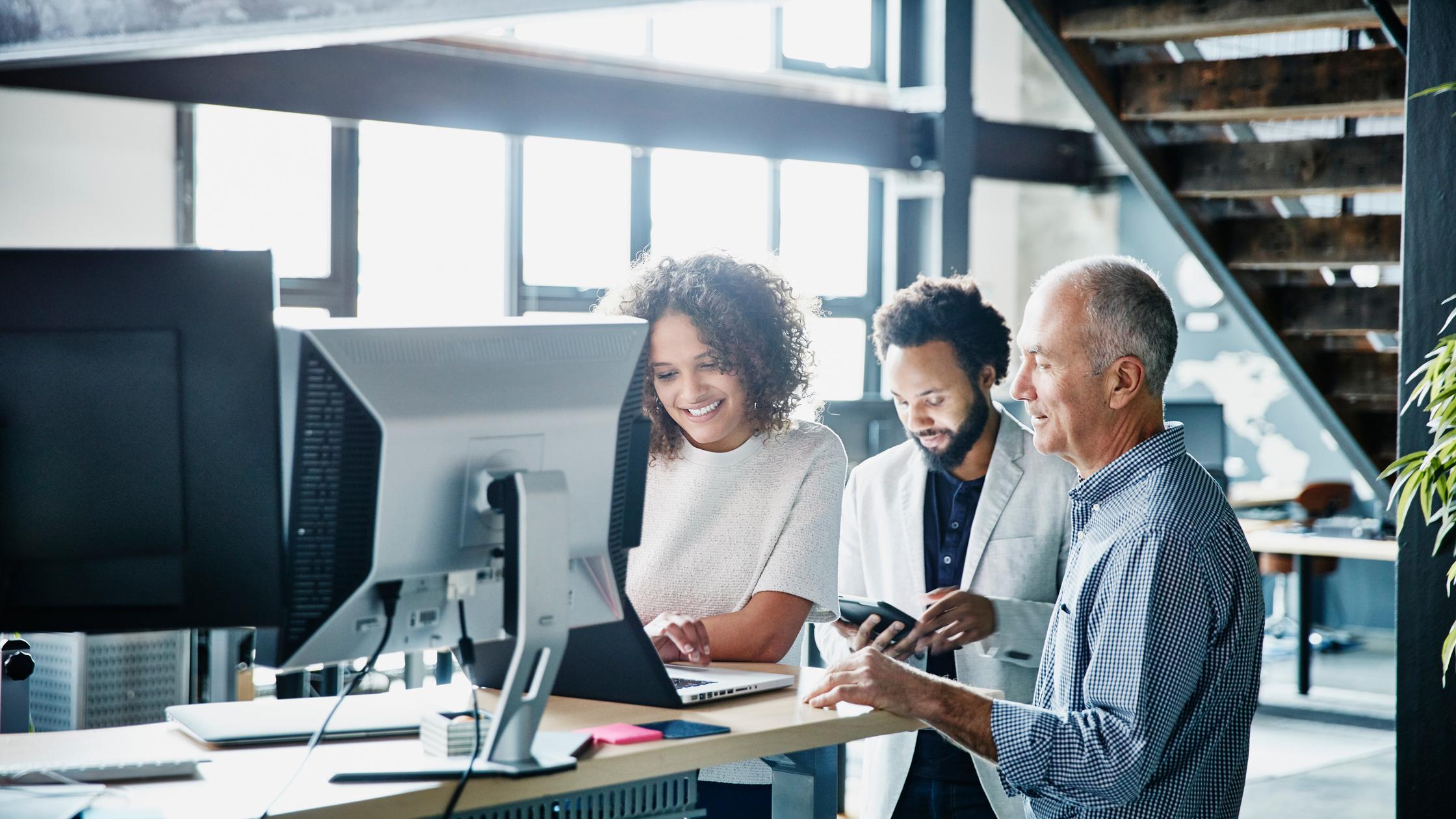 Mitarbeiter besprechen ein Projekt auf einem Laptop in einem Hightech-Büro